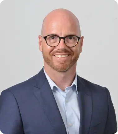 Portrait Foto eines lächelnden Mannes mit Glatze und Brille
